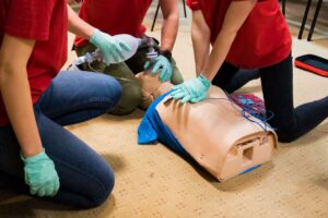 Students performing CPR and ventilation on a training manikin in class