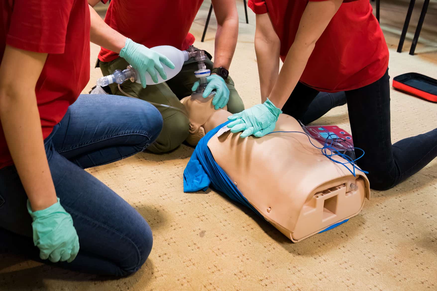 Students performing CPR and ventilation on a training manikin in class